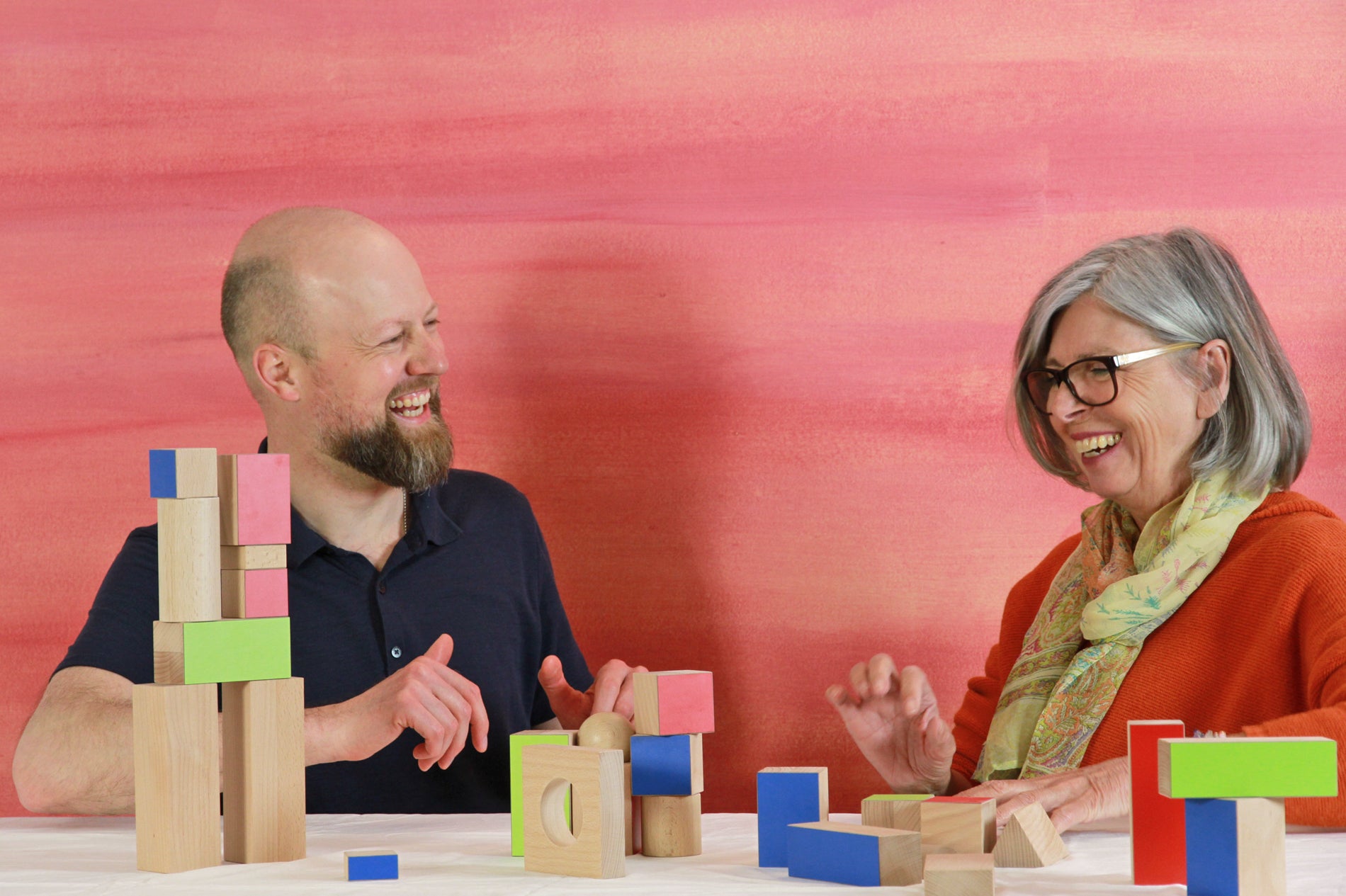Two adults are shown playing FutureCity, a team building activity using blocks and photo cards.