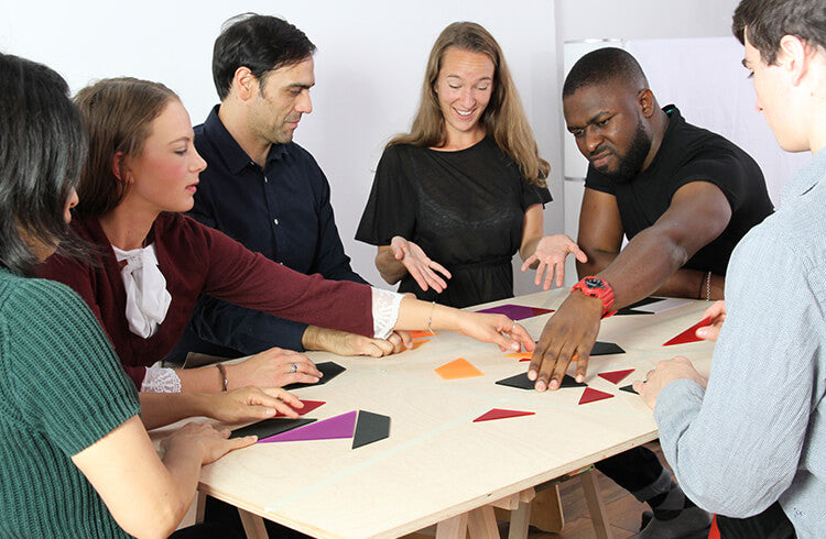 Several adults use Metalog Team Squared, a team building puzzle for improving group dynamics