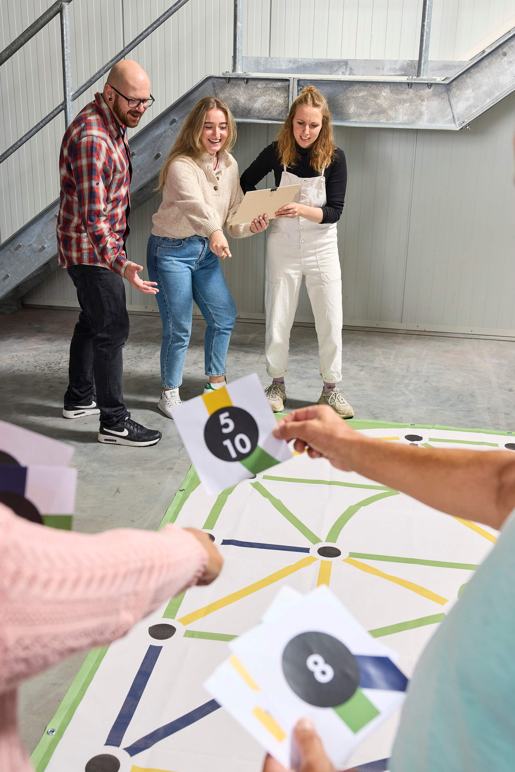 Three people with a drawing gesture toward a maze on the floor, trying to solve it
