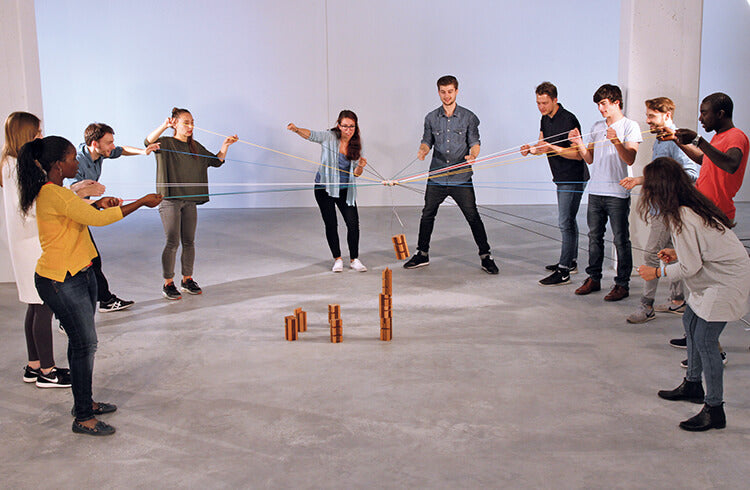 A work team stacks wooden blocks using strings attached to a crane in Metalog's Tower of Power 