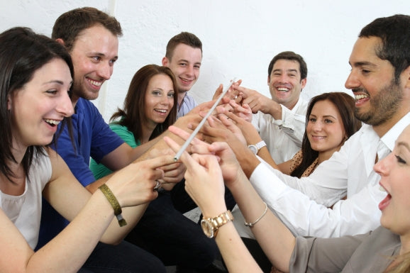 Eight adults hold FloatingStick on their index fingers in this fun way to improve team coordination.