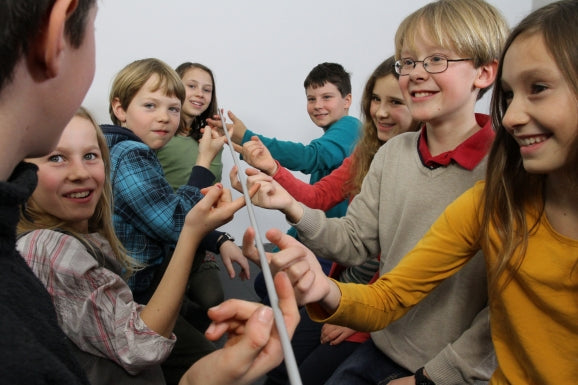 A group of children uses FloatingStick from Metalog to learn about teamwork and self-organization.