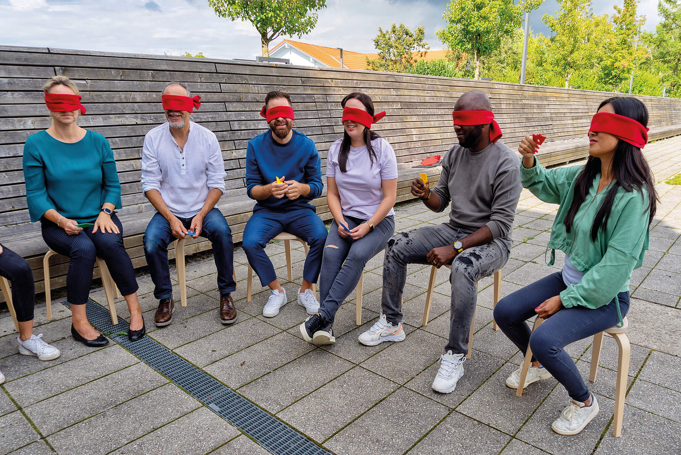 Six blindfolded adults sitting in a circle, describe their plastic CommuniCards shapes to each other