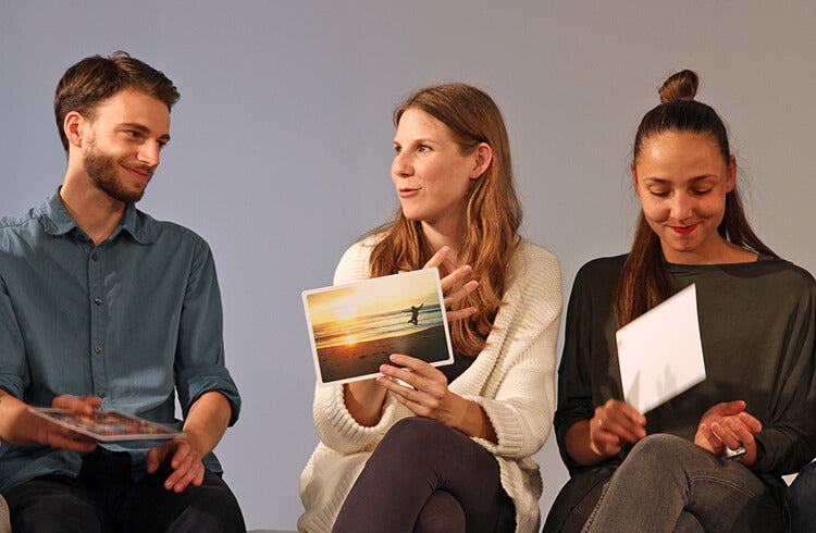 Three seated adults hold an Emotion Card, a fun way to start team dialogue and group reflection 