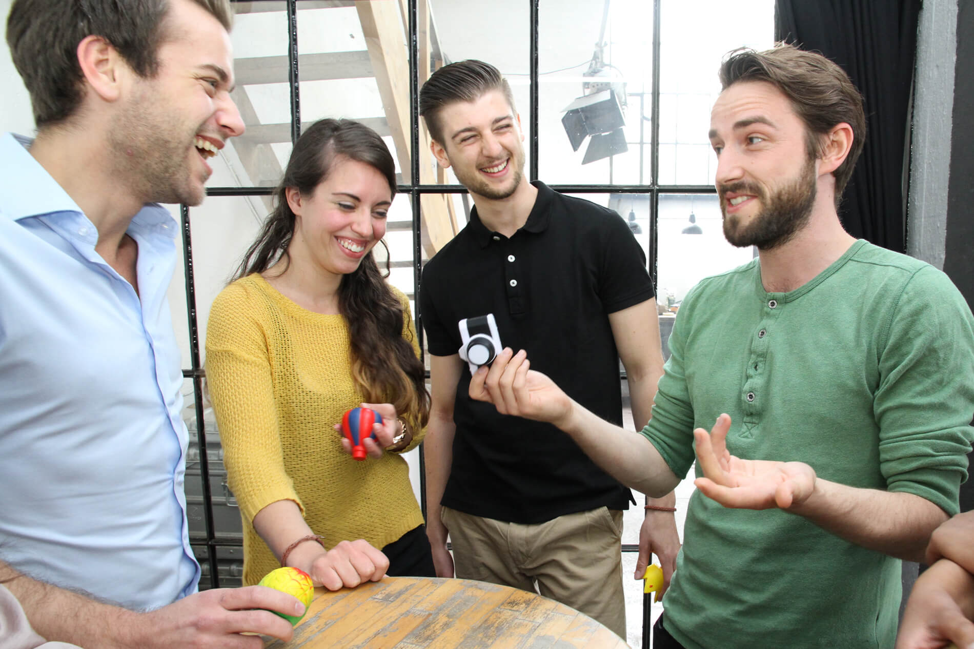 Four smiling adults each hold a unique foam shape from Metalog Tools Facilitation Balls