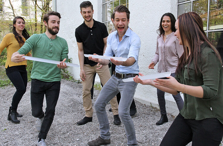 Three young adults work quickly to keep a ball rolling through Pipeline, a team building activity