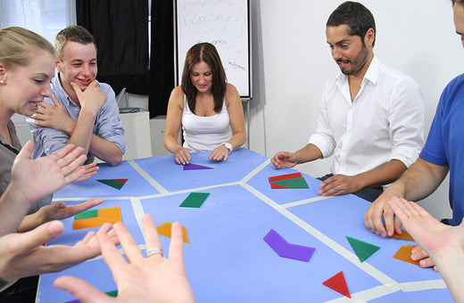 Adults at team building workshop use non verbal communication to solve puzzle game, Team²